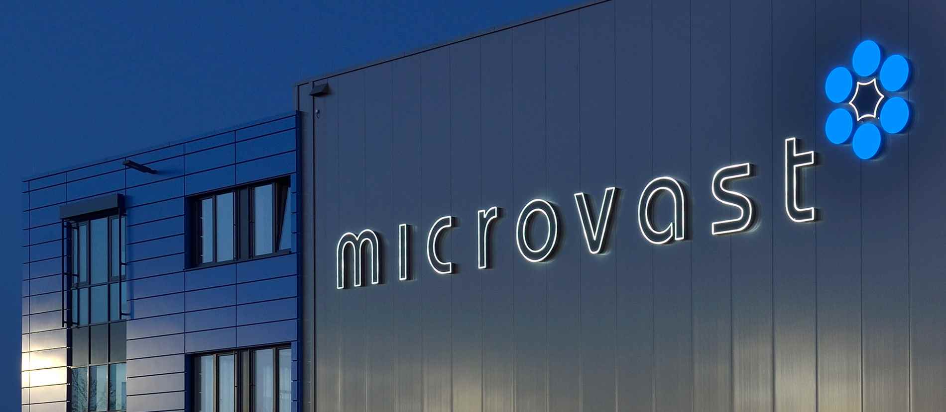 Beleuchtete Fassadenbeschriftung des Microvast-Gebäudes in Ludwigsfelde. Die modernen, hellen Leuchtbuchstaben und das auffällige blaue Logo heben sich klar gegen die metallische Fassade ab und unterstreichen das innovative Erscheinungsbild des Unternehmens.
