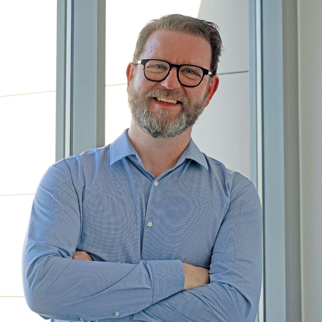 Der Kundenberater für Lichtwerbung Dresden Mike Klügel verschränkt die Arme und lächelt